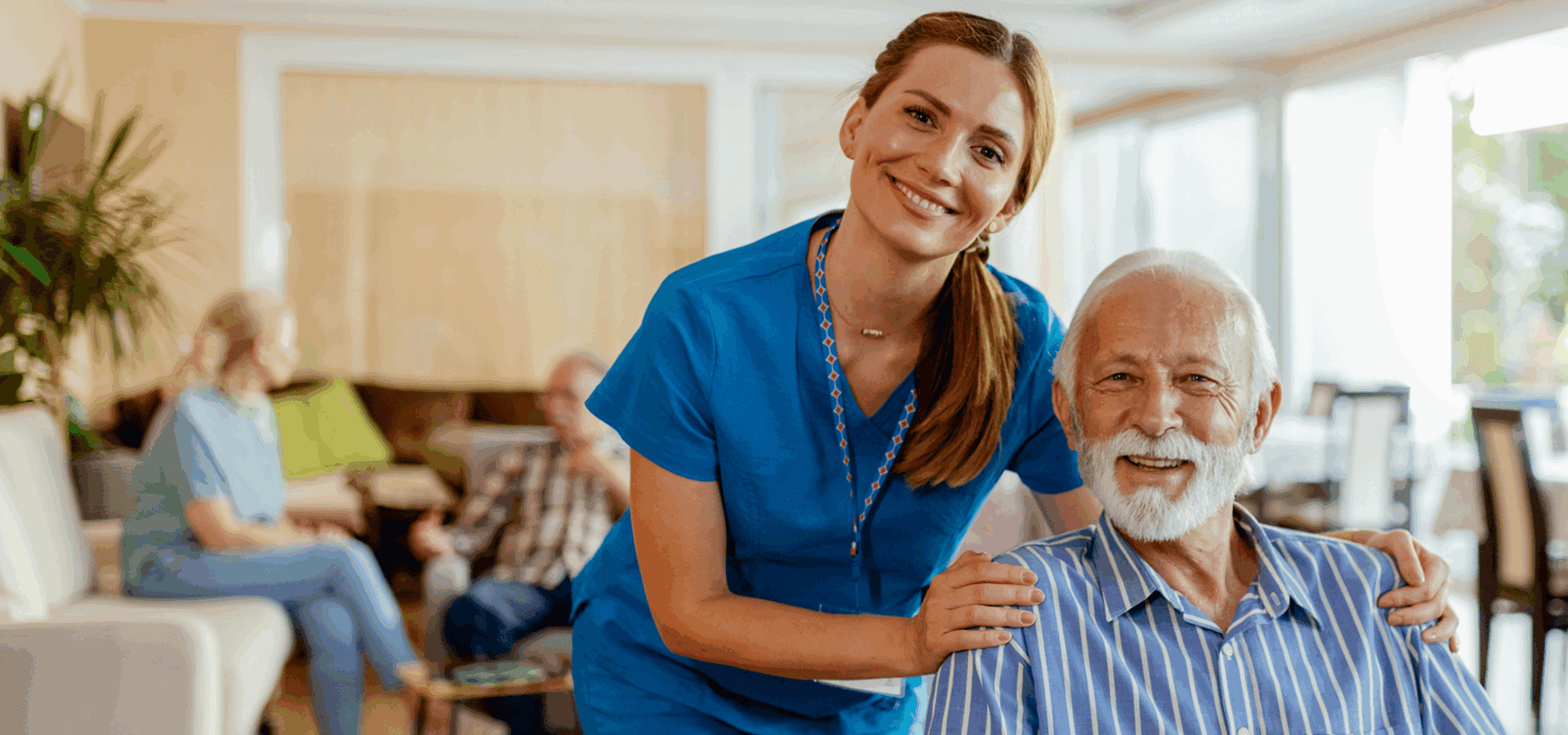 Caregiver smiling with elderly man in lounge.